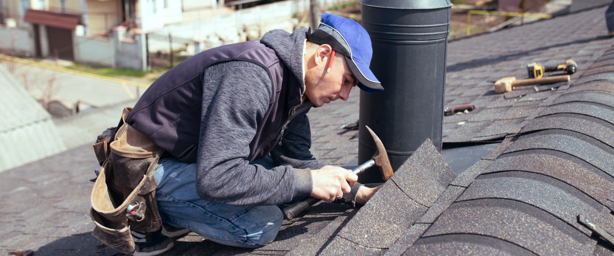 A roofer repairing tiles on a roof.